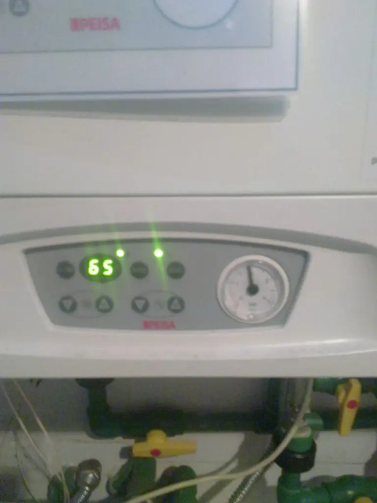 Wall-hung gas boiler running, with the system pressure gauge visible
