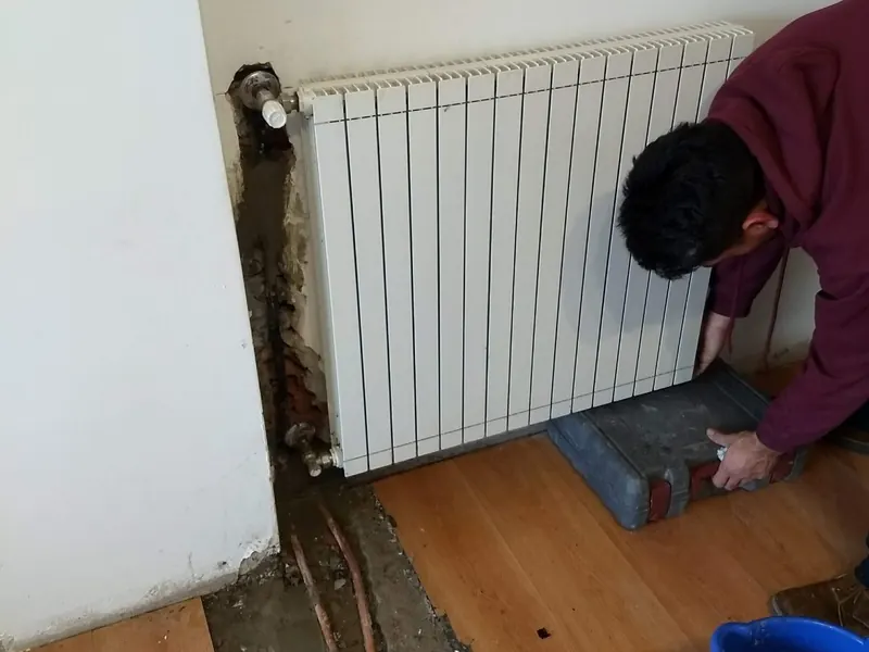 Técnico instalando un radiador de calefacción en una vivienda