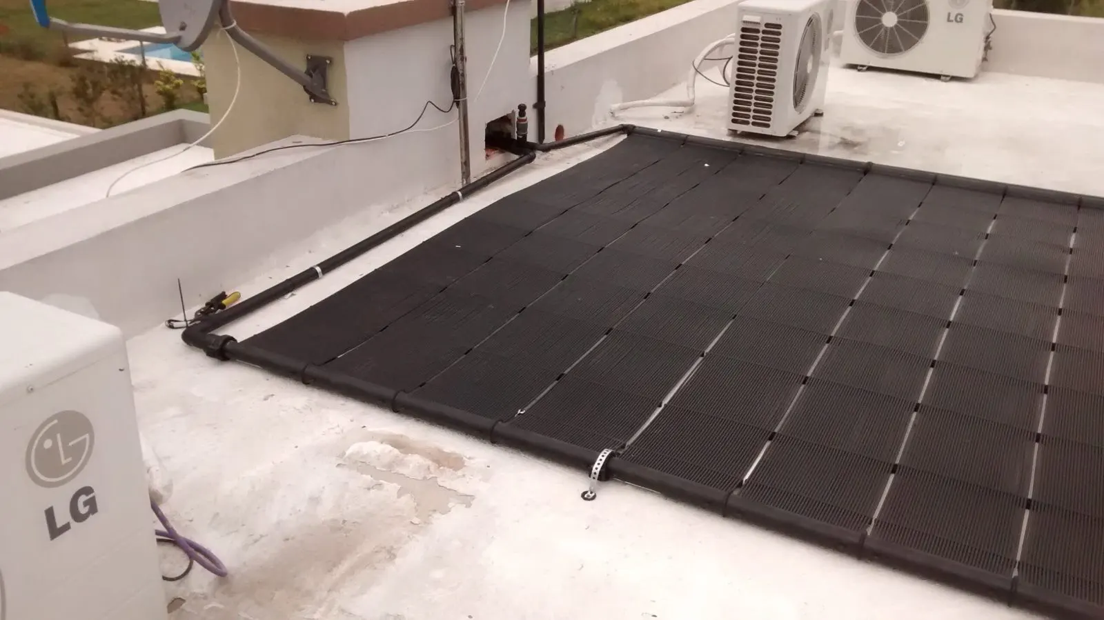 Campo de captadores solares para calentar el agua de una piscina, instalado en cubierta