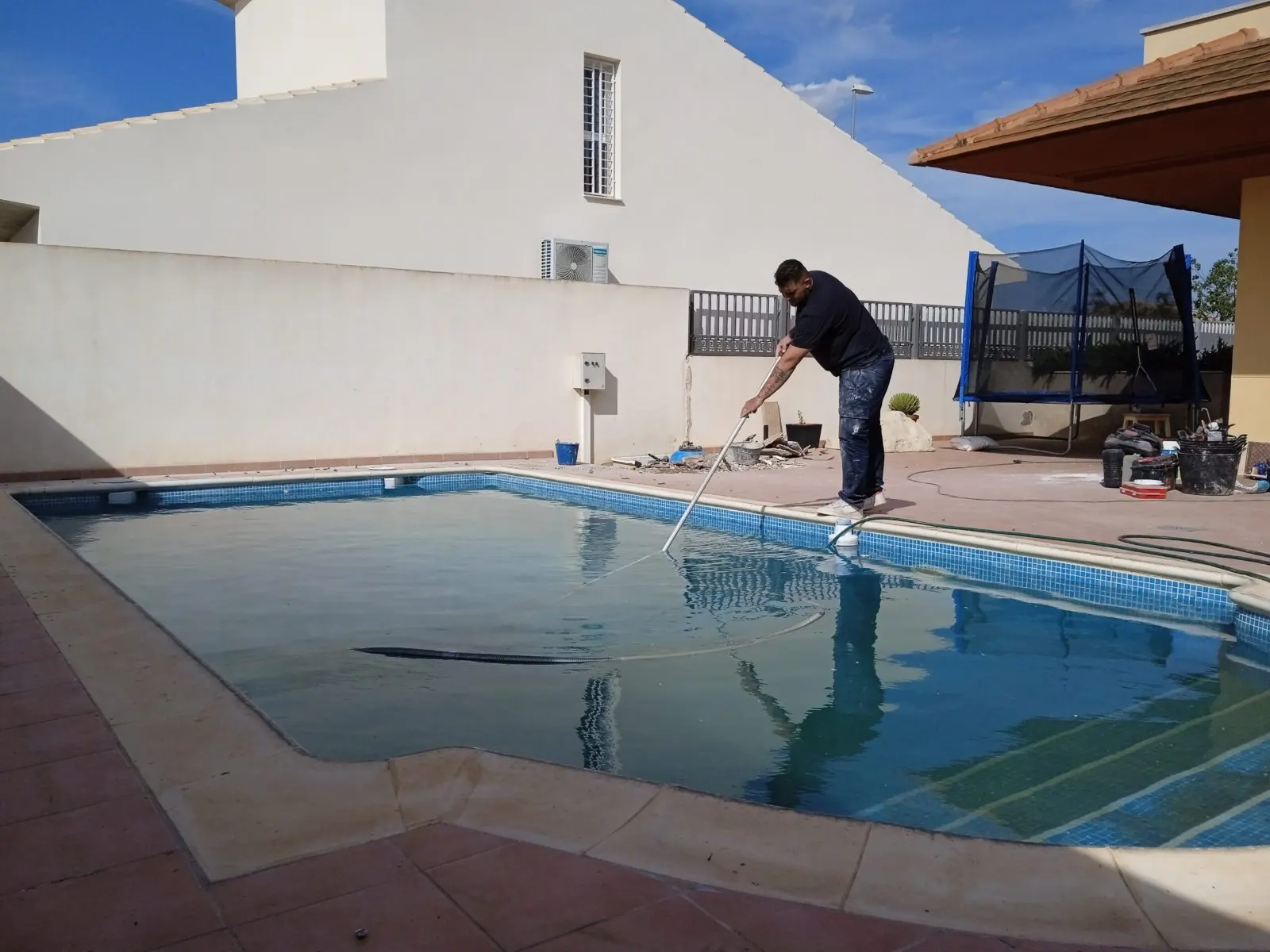 Technician working at the edge of a pool during a maintenance visit